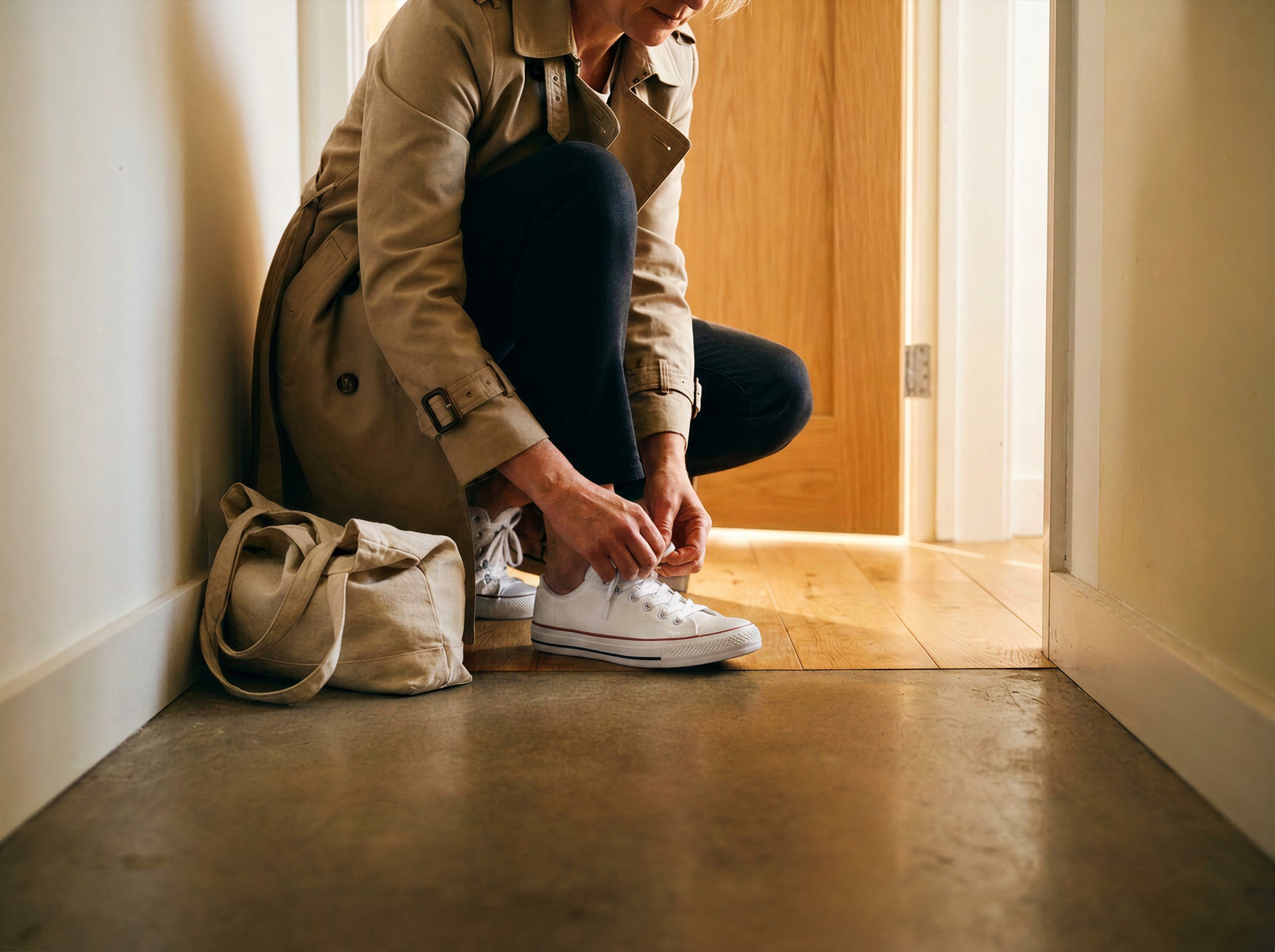 Person zieht sich zu Hause im Flur ihre weißen Sneaker an